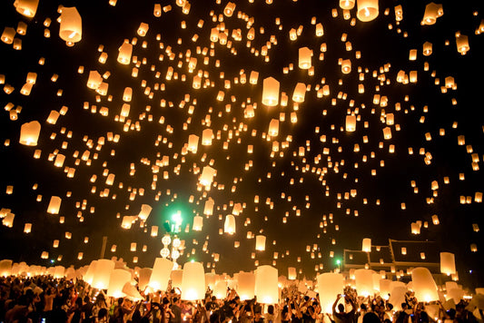 Thousands of sky lanterns rising over a crowd during Yi Peng near Chiang Mai