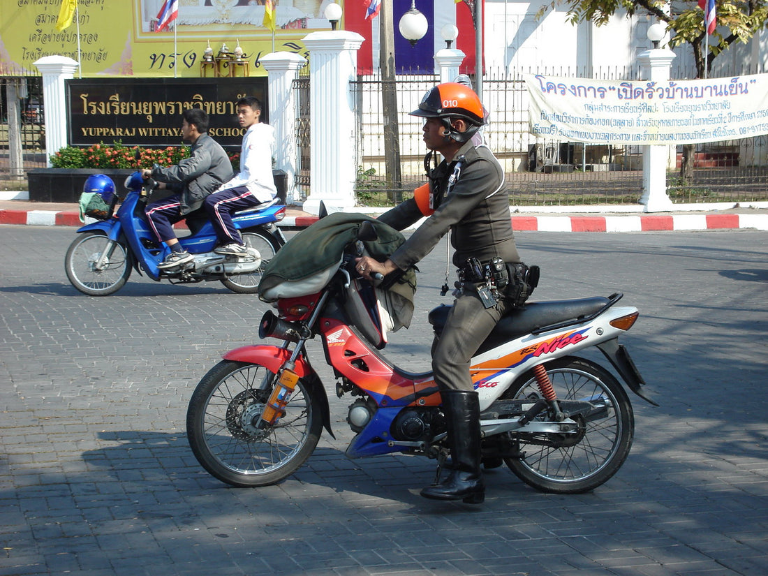 Thai police officer next to a motorbike at a checkpoint